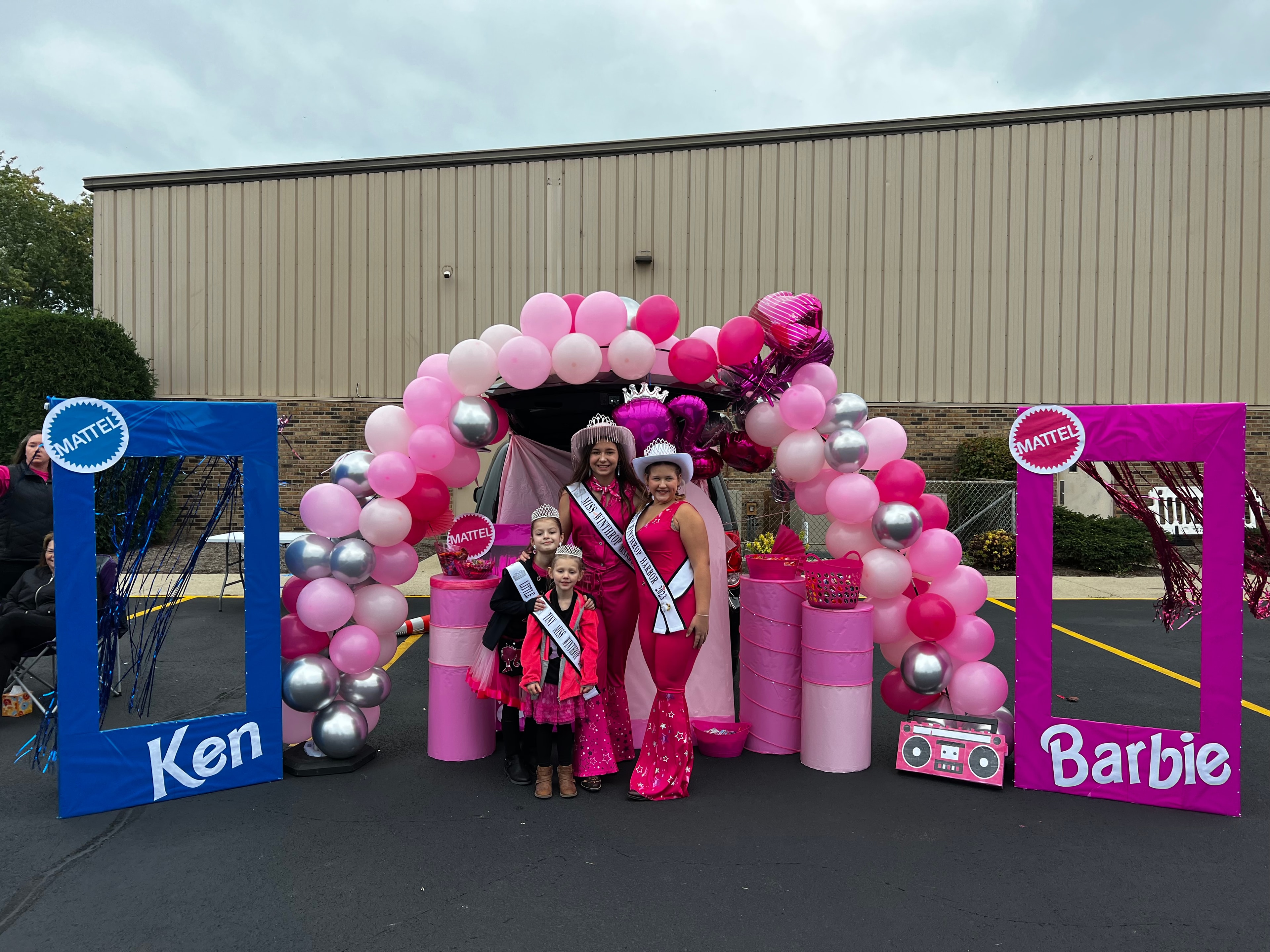 Barbie-themed trunk with balloon arch and pageant queens
